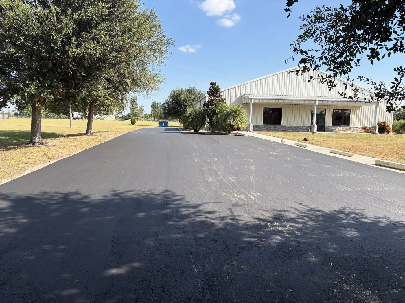 Large commercial driveway leading up to a metal building, freshly paved